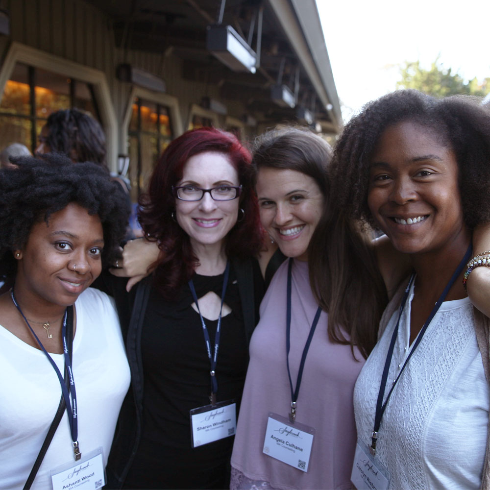 Four women smiling with a red tint overlay