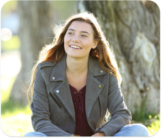 A woman smiling while sitting outside in the grass