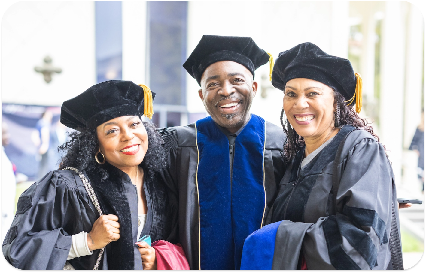 3 people smiling in graduation caps and gowns