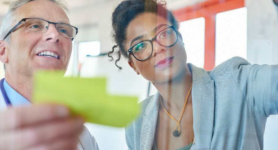 two people wearing glasses looking at glass screen