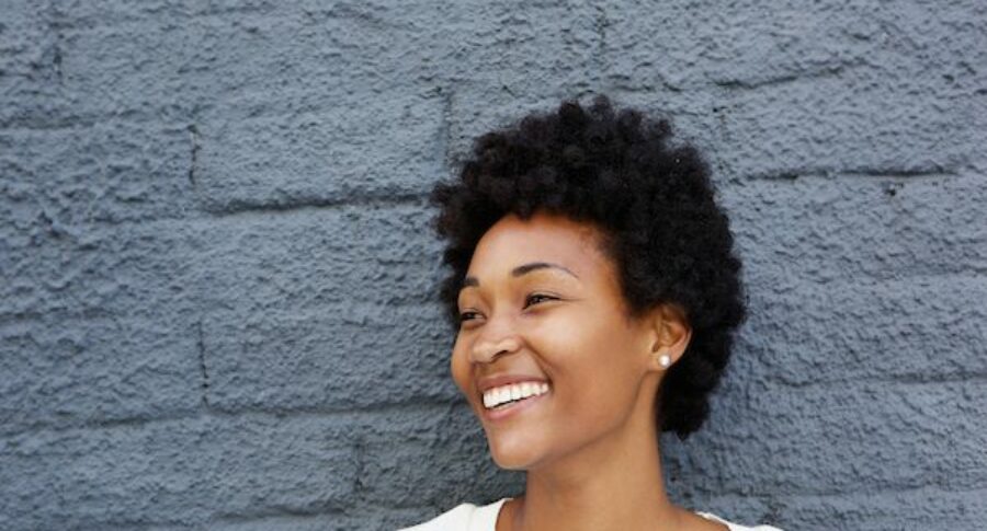 woman smiling against gray brick wall