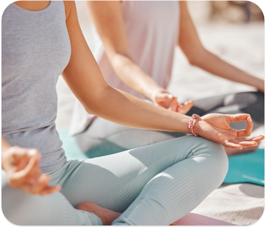 Two people meditating on a beach.