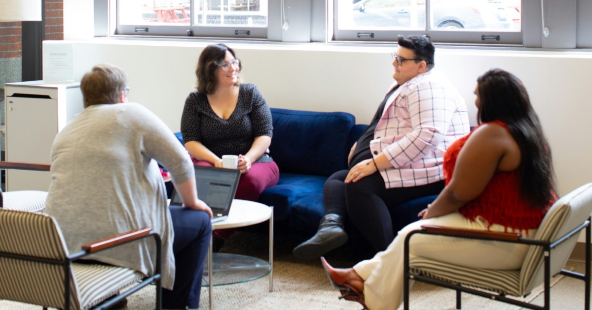 Four women sitting in a circle talking.