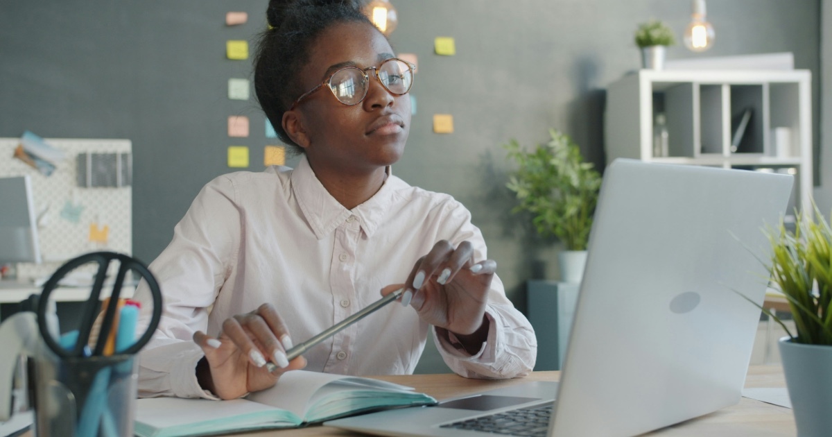 Young woman with glasses looking up from a laptop